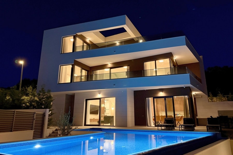 Luxusvilla mit Swimmingpool und beleuchteter Fassade am Abend