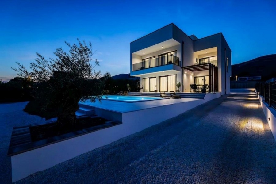 Moderne Villa bei Nacht mit beleuchtetem Pool