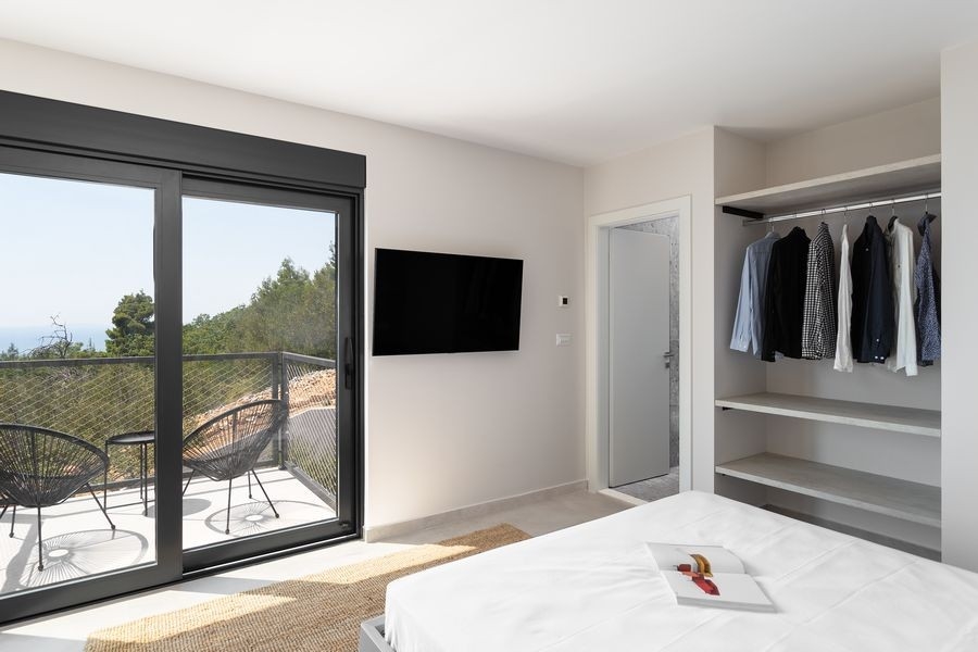 Schlafzimmer mit offenem Kleiderschrank und Balkon
