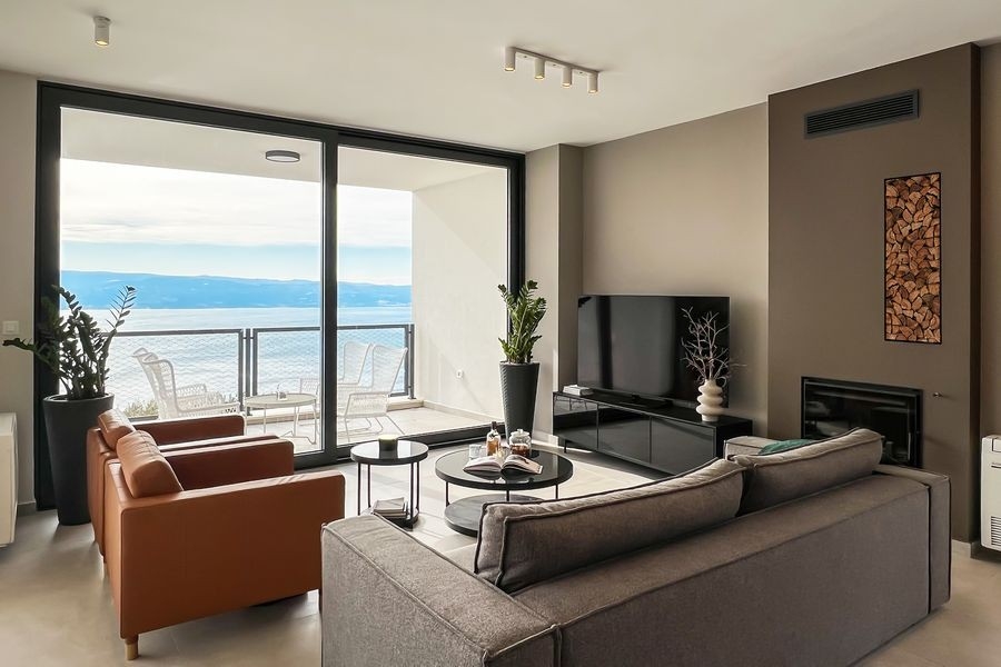 Wohnzimmer mit Kamin und Panoramafenster zum Meer