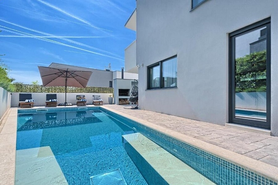 Swimmingpool mit Sonnenschirm und Liegestühlen an der Villa
