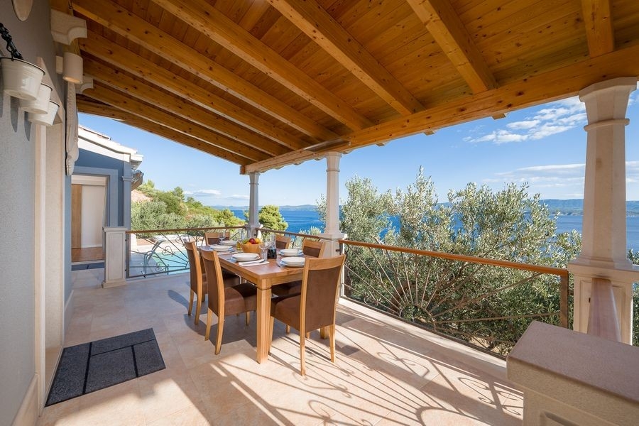 Überdachte Terrasse mit gedecktem Tisch und Meerblick