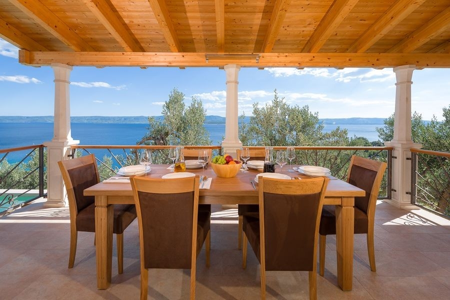 Überdachte Terrasse mit großem Tisch und Stühlen