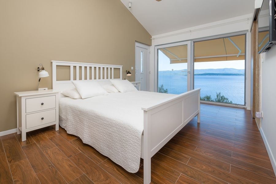 Schlafzimmer mit Doppelbett und großen Fenstern zum Meer