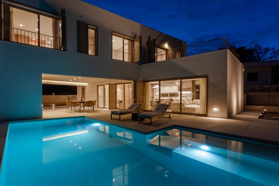 Beleuchtete Villa mit Pool in der Abenddämmerung