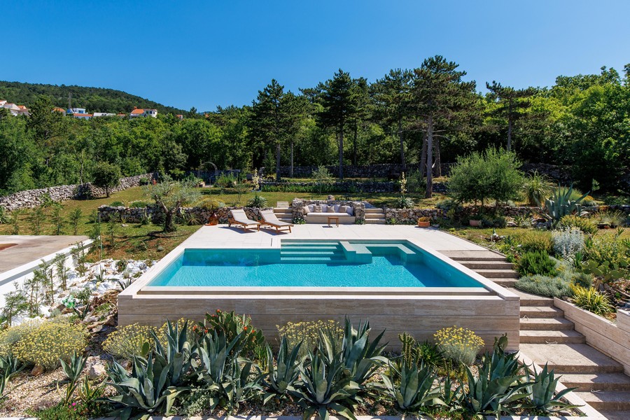 Swimmingpool mit Sonnenliegen und Gartenanlage
