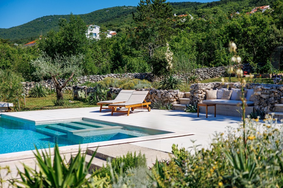 Poolbereich mit Sonnenliegen und Steingarten