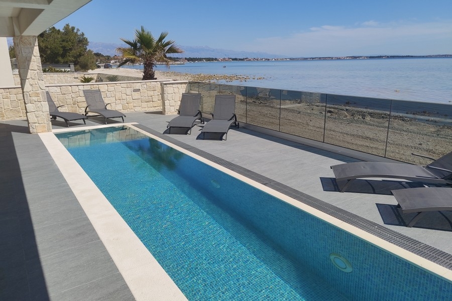 Pool mit Sonnenliegen direkt am Meer auf der Insel Vir