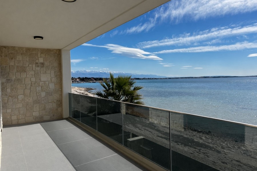 Überdachte Terrasse mit Glasgeländer und Meerblick
