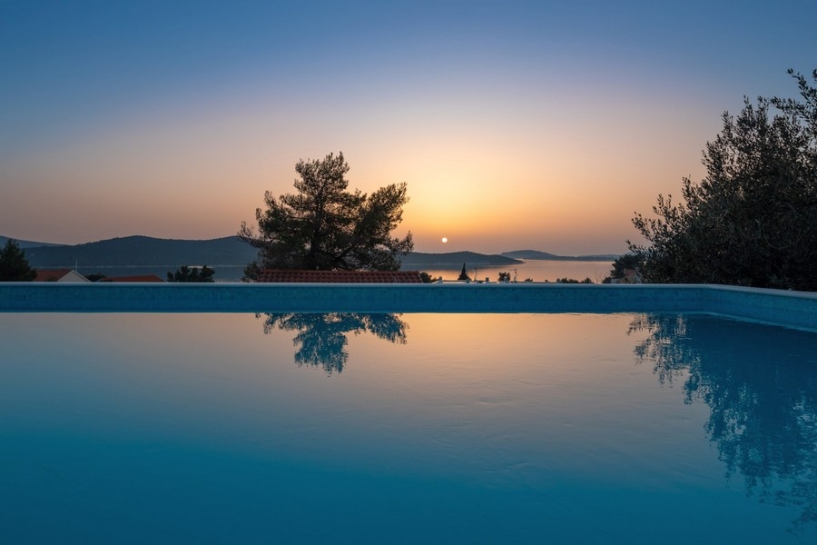 Infinitypool bei Sonnenuntergang mit Panoramablick auf das Meer