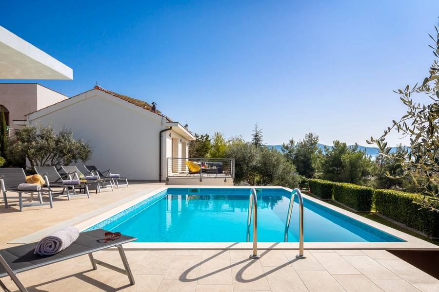 Swimmingpool mit Sonnenliegen und Meerblick