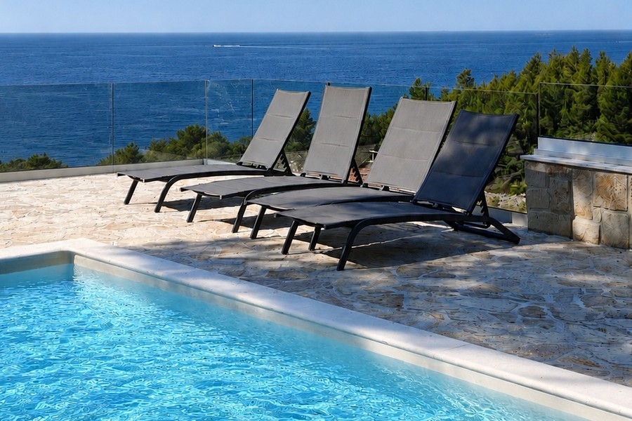 Swimmingpool mit Sonnenliegen und Meerblick