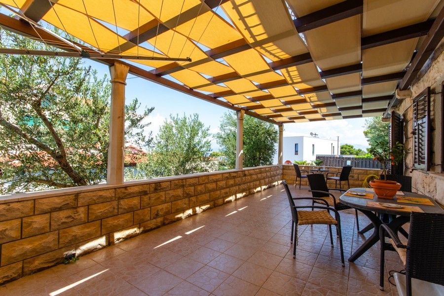 Überdachte Terrasse mit Steinmauer und Meerblick