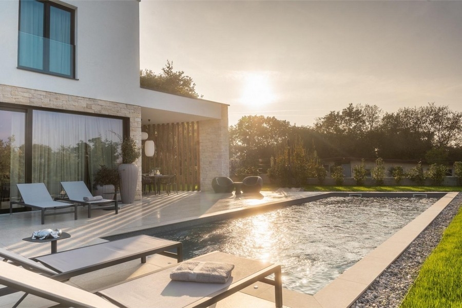 Pool mit Sonnenliegen bei Sonnenuntergang