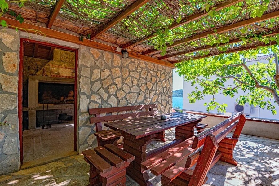 Überdachte Sommerküche mit Grill und Holztisch