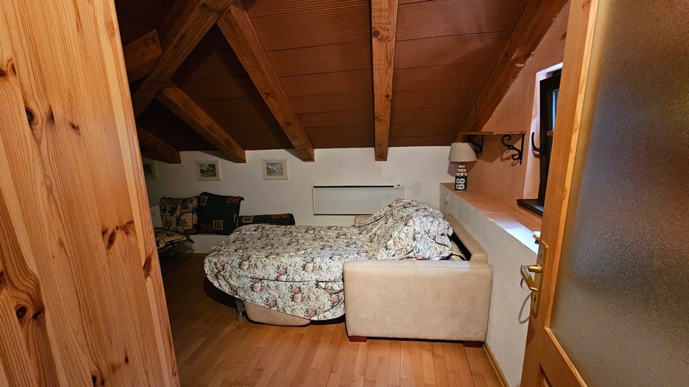 Dachzimmer mit Bett und Holzbalken