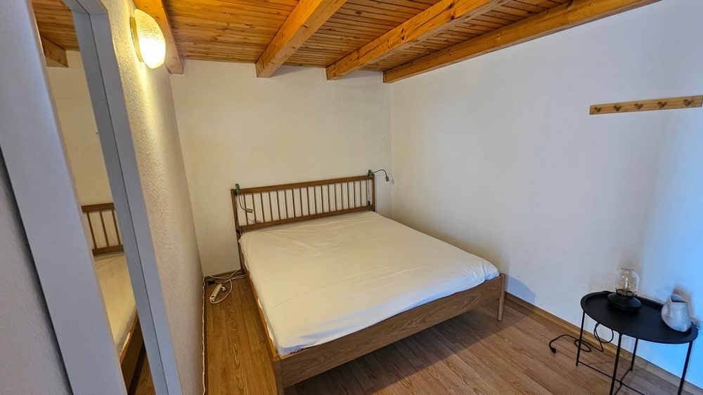 Schlafzimmer mit Doppelbett und Holzbalkendecke