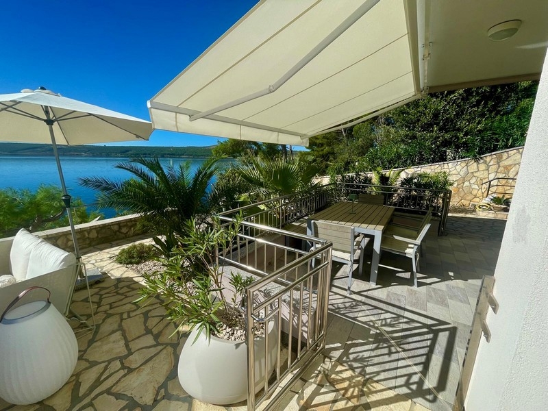 Überdachte Terrasse mit Esstisch und Meerblick