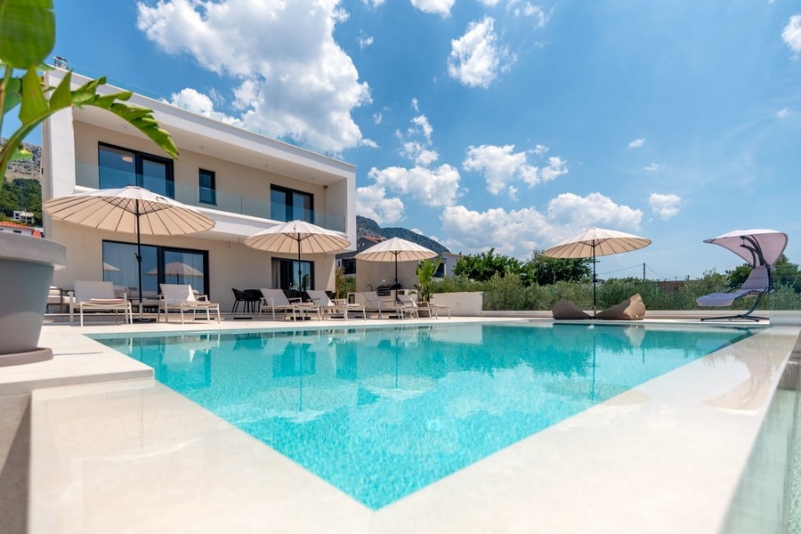 Pool mit Sonnenliegen vor der Villa