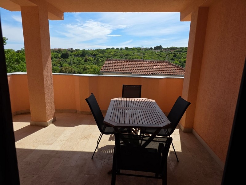 Überdachte Terrasse mit Sitzgruppe und Blick ins Grüne