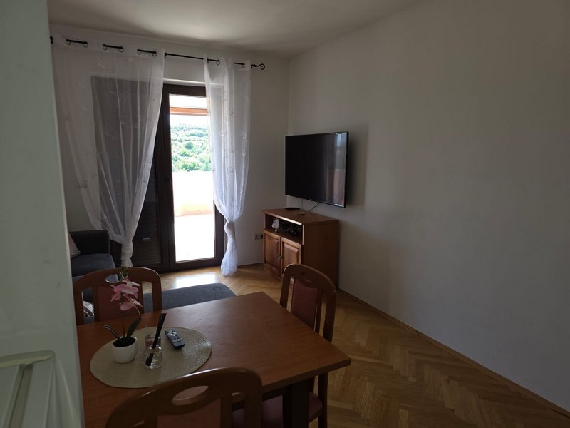 Wohnraum mit Tisch, Fernseher und Terrassentür