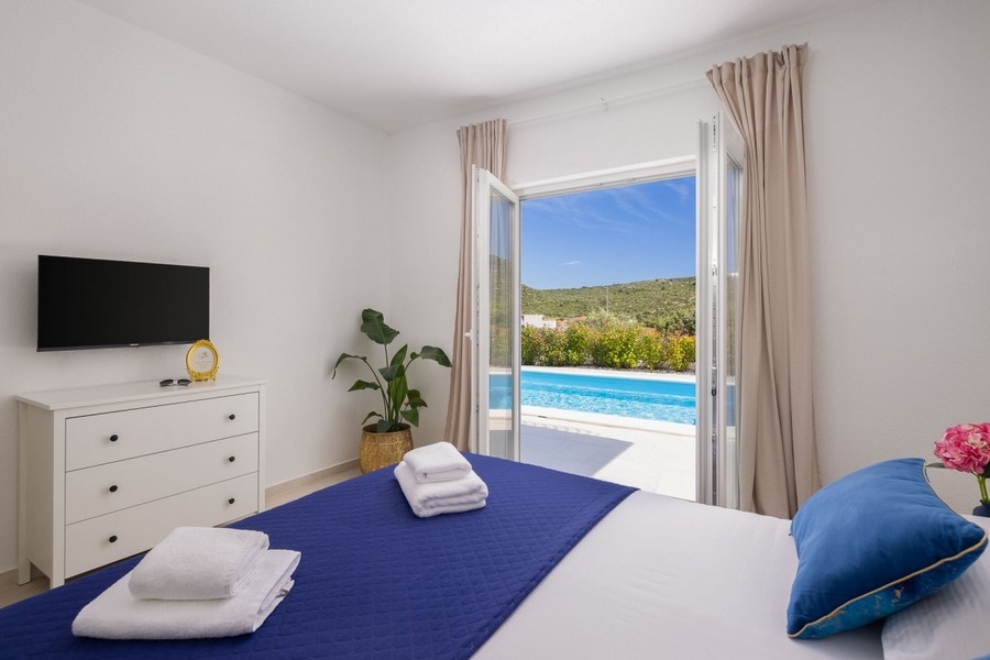 Schlafzimmer mit Doppelbett und Zugang zum Pool