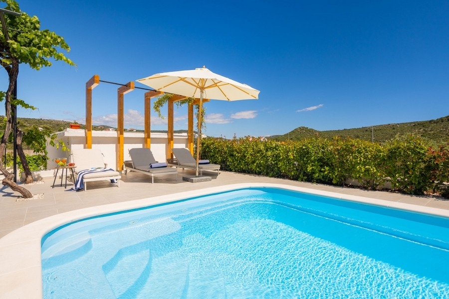 Swimmingpool mit Sonnenliegen und Pergola