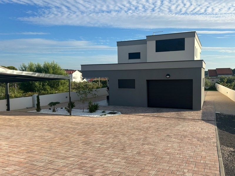 Hausansicht mit Garage und gepflastertem Vorplatz