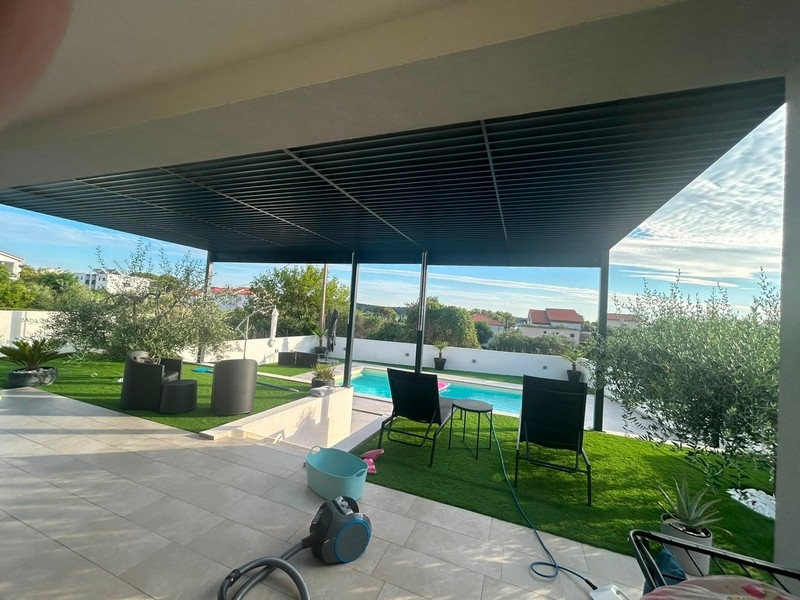 Überdachte Terrasse mit Sitzgruppe, Rasen und Pool
