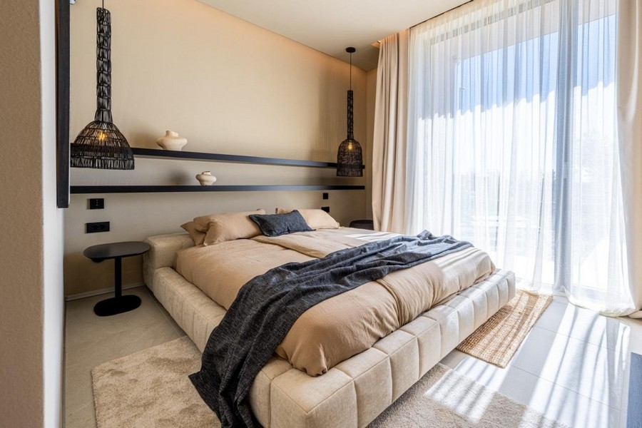 Schlafzimmer mit Doppelbett und bodentiefen Fenstern