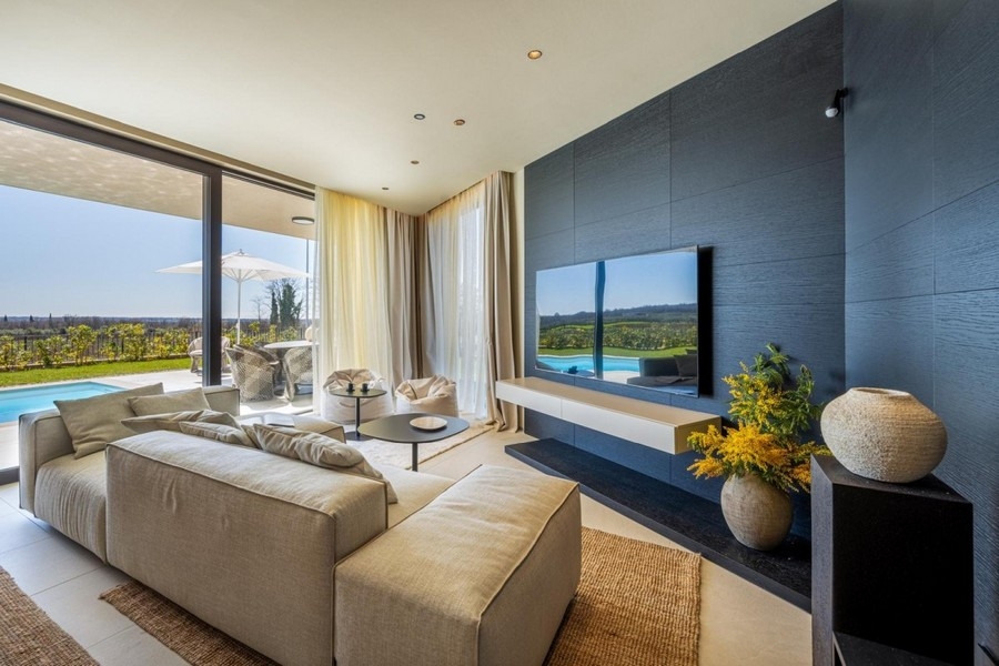Wohnbereich mit Sofa, TV-Wand und Blick ins Grüne