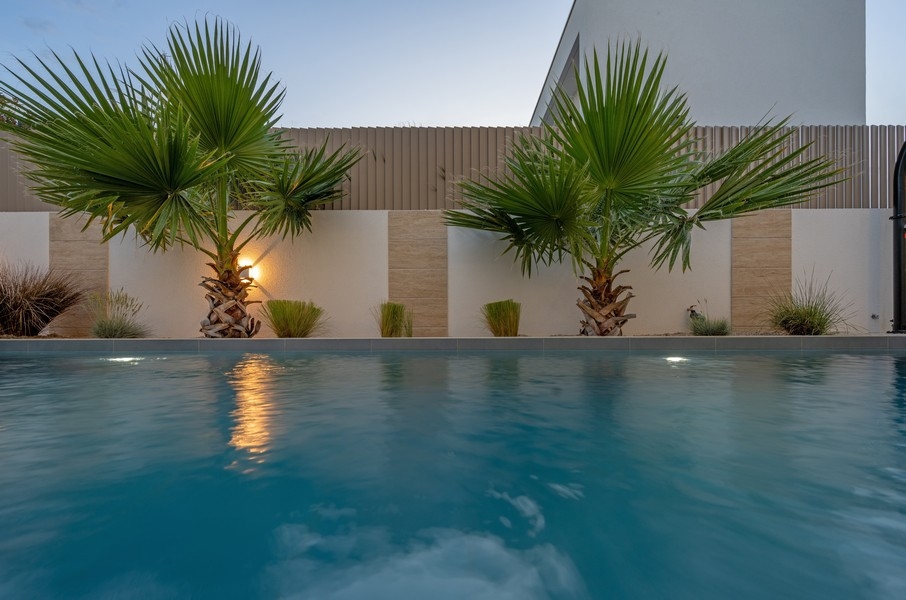 Swimmingpool mit Palmen und beleuchteter Poolterrasse