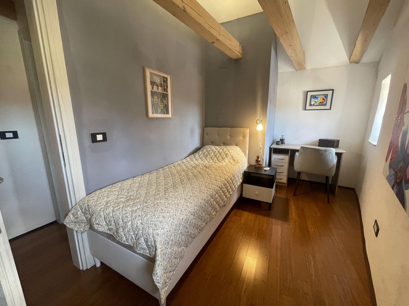 Schlafzimmer mit Einzelbett und Schreibtisch unter dem Dach