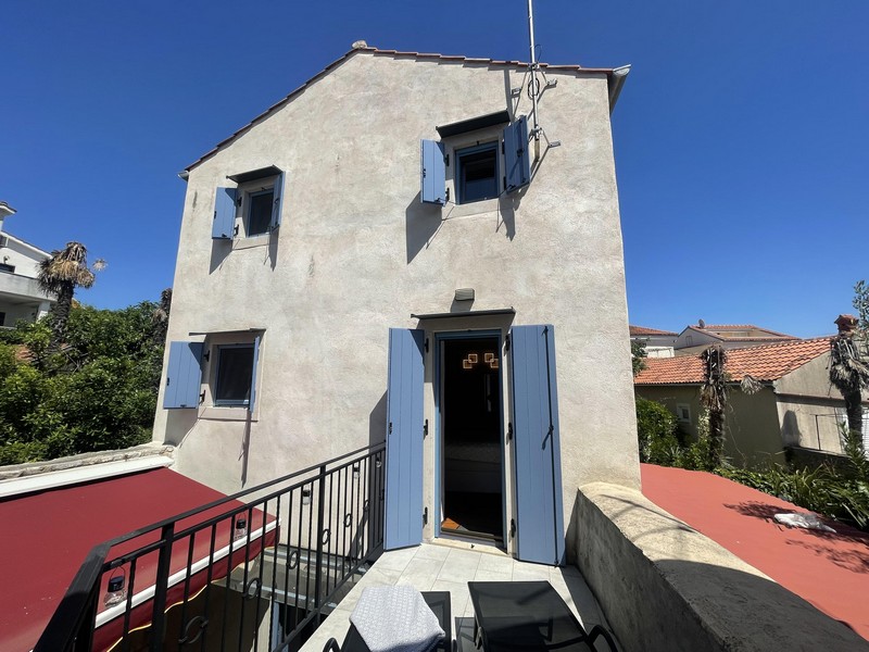 Steinhaus mit hellblauen Fensterläden und Dachterrasse in Krk