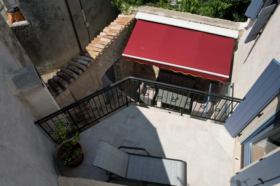 Terrasse mit roter Markise und Sitzbereich im Innenhof