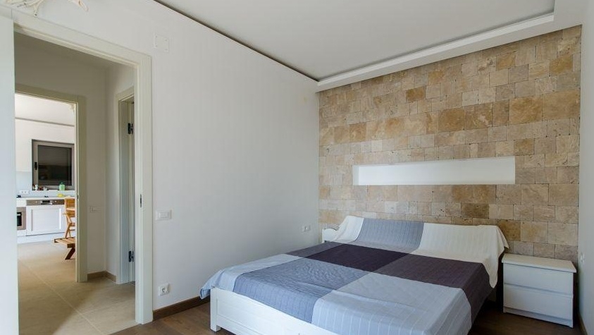 Schlafzimmer mit Natursteinwand und Doppelbett
