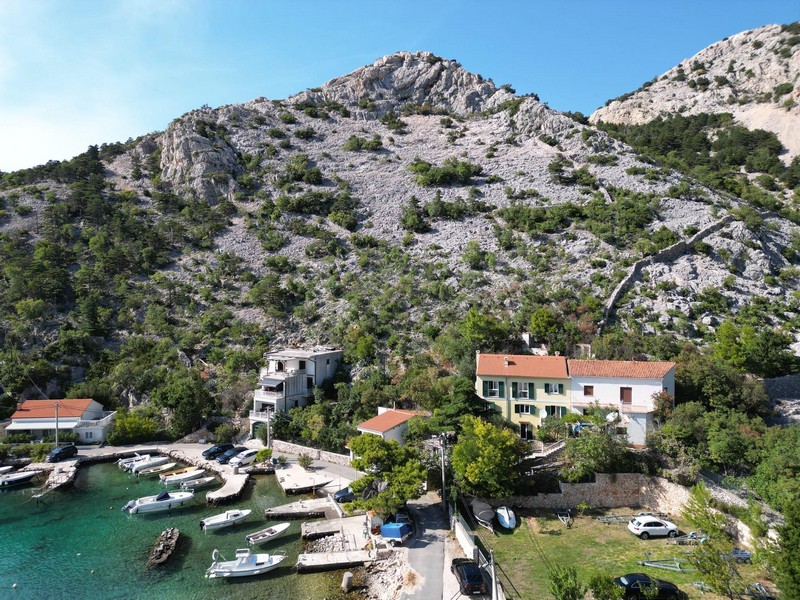 Bucht mit klarem Wasser und den Bergen des Velebit von oben