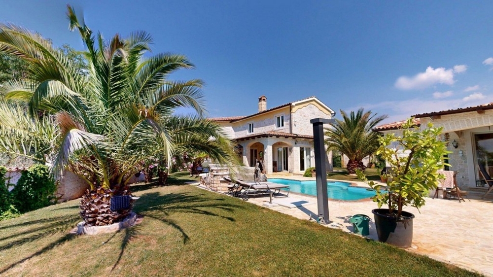 Mediterraner Garten mit Palmen und Pool vor dem Haus