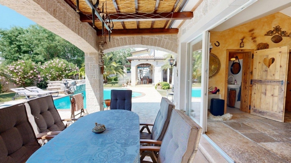 Überdachte Terrasse der Konoba mit Esstisch und Blick zum Pool