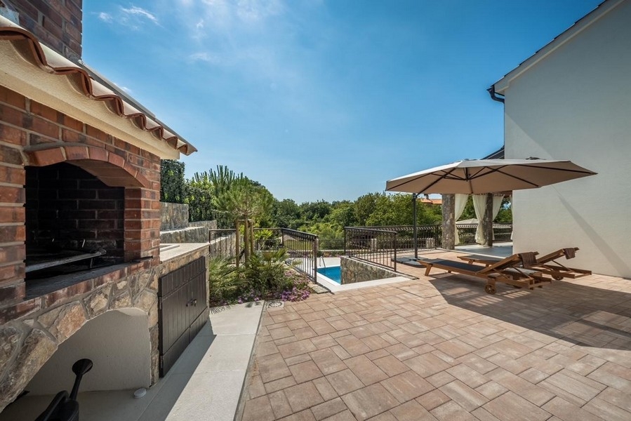 Überdachte Terrasse mit Außenkamin und Blick auf den Pool