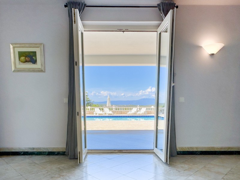 Blick durch die Terrassentür auf Pool und Meer