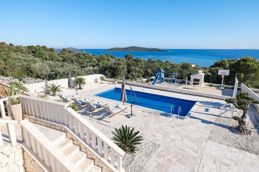 Swimmingpool mit Liegen und Blick auf das Meer