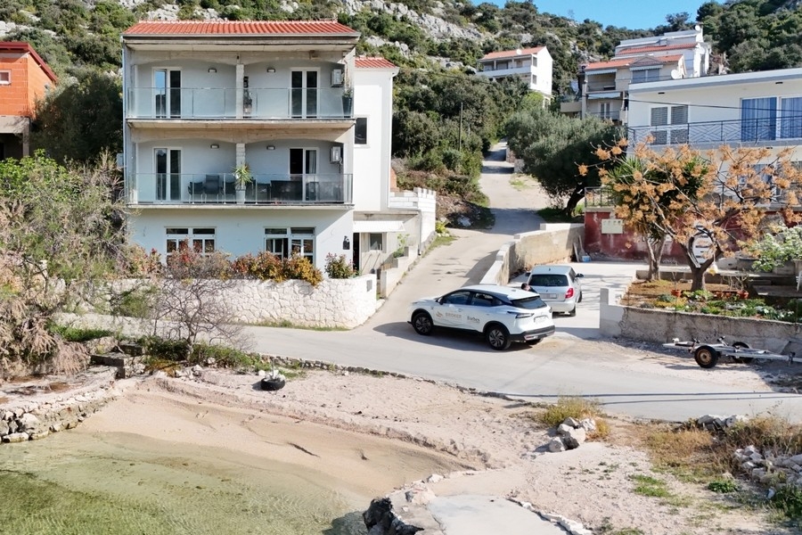 Dreistöckiges Mehrfamilienhaus mit Balkonen direkt an der Bucht