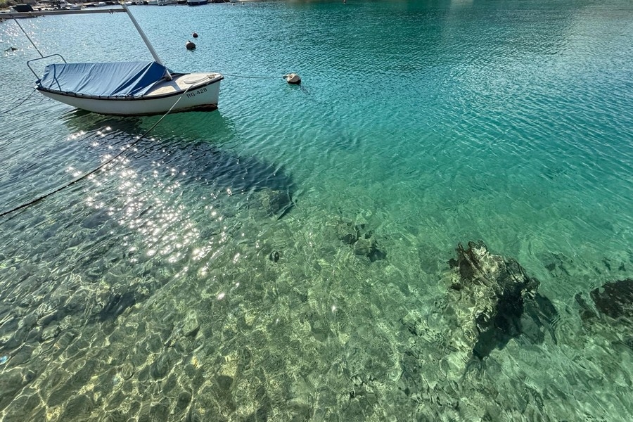 Klares Wasser der Bucht mit Boot am Ufer