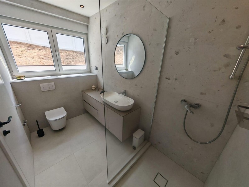 Badezimmer mit Dusche und rundem Spiegel