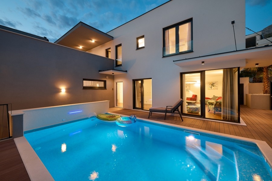 Beheizter Swimmingpool vor der Villa am Abend