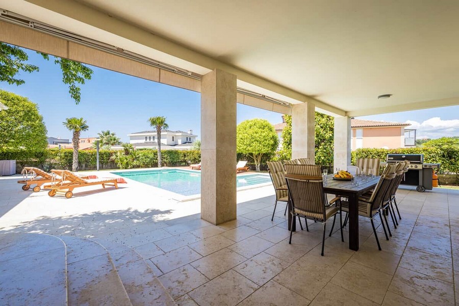 Überdachte Terrasse mit Esstisch am Pool
