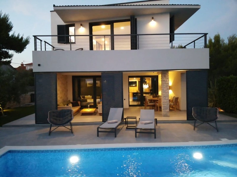 Hausfront mit Terrasse und beleuchtetem Pool