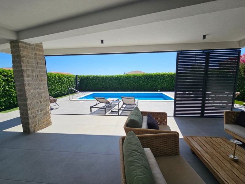Überdachte Terrasse mit Loungemöbeln und Blick zum Pool