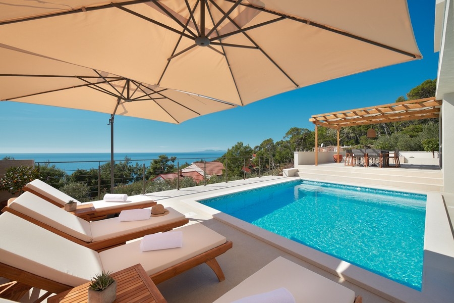 Poolterrasse mit Sonnenliegen und Sonnenschirm